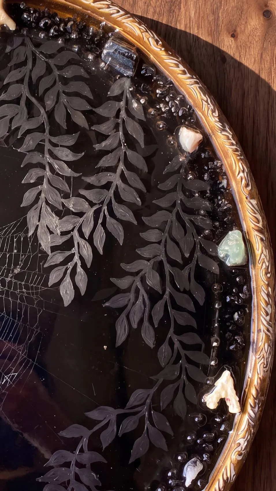 Detail — foliage and stones around an obsidian mirror.